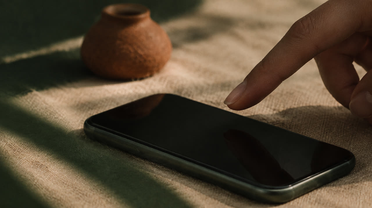 A fingertip about to touch a phone screen resting on linen